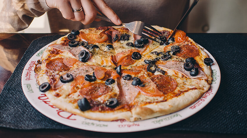 woman cutting a slice of piiza