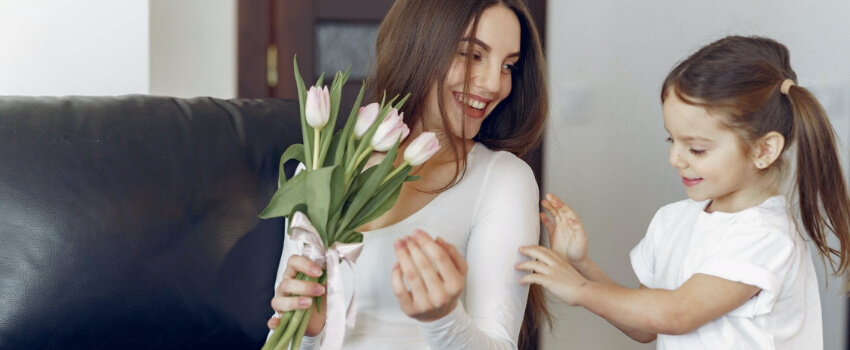 a girl offering flowers to her mom