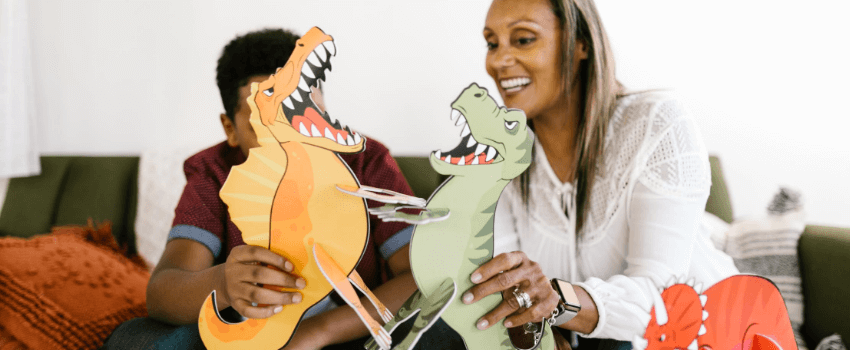 woman and kid playing with cardboard dinosaurs