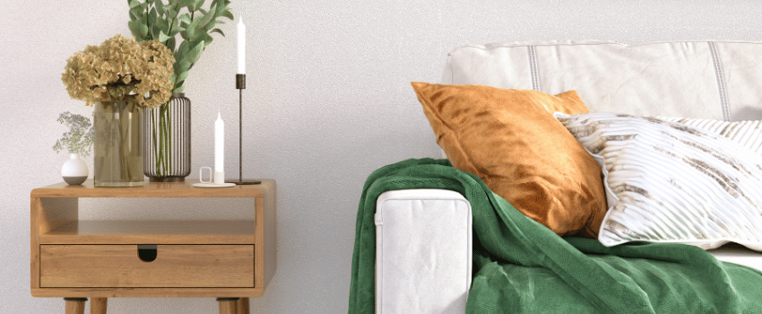 A white couch with green and orange pillows provides a cheerful and comfortable seating option, bought using home teacher discounts.