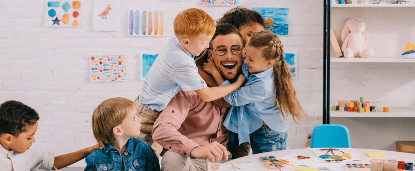 A group of children and a teacher sit at a classroom table, surrounded by colorful educational materials purchased using the best teacher discounts.